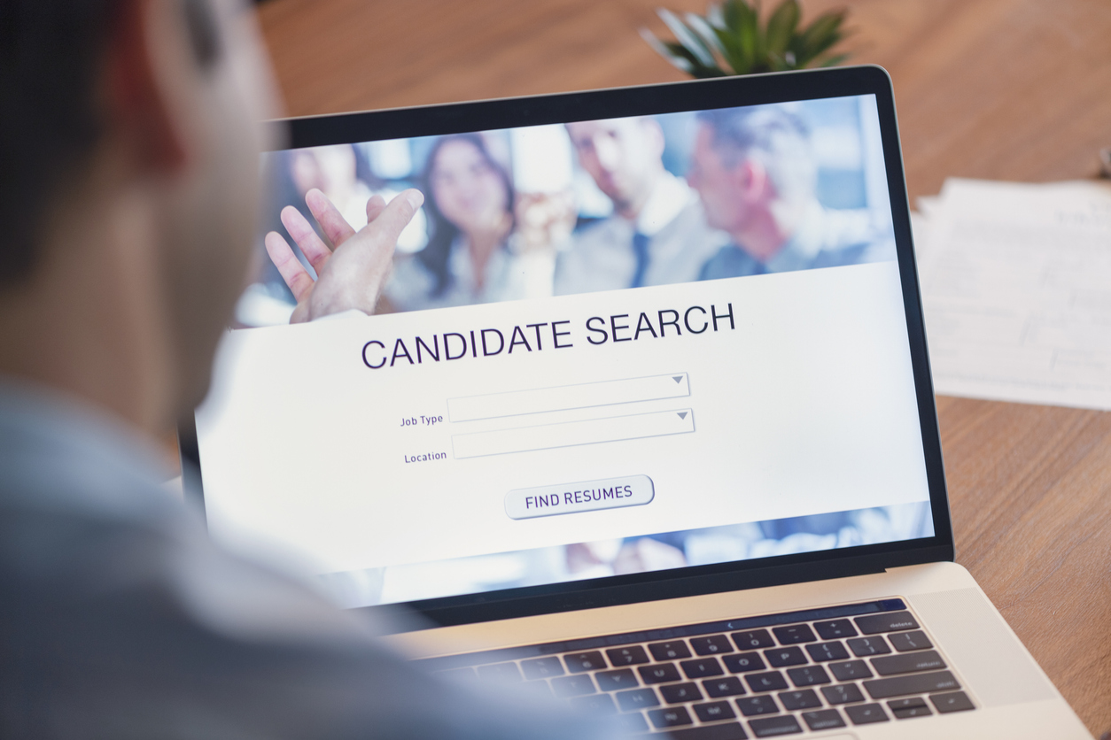 Man researches candidates on laptop as part of hiring process.