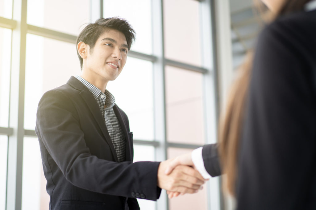 Male jobseeker shakes hands with recruiter at a job fair.