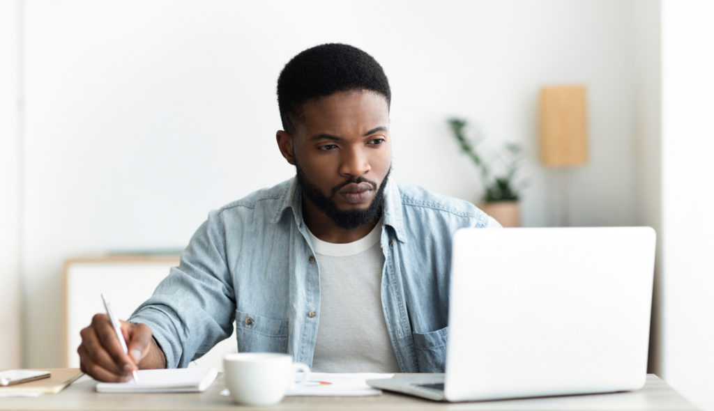 Man uses laptop to write his resume using resume tips.