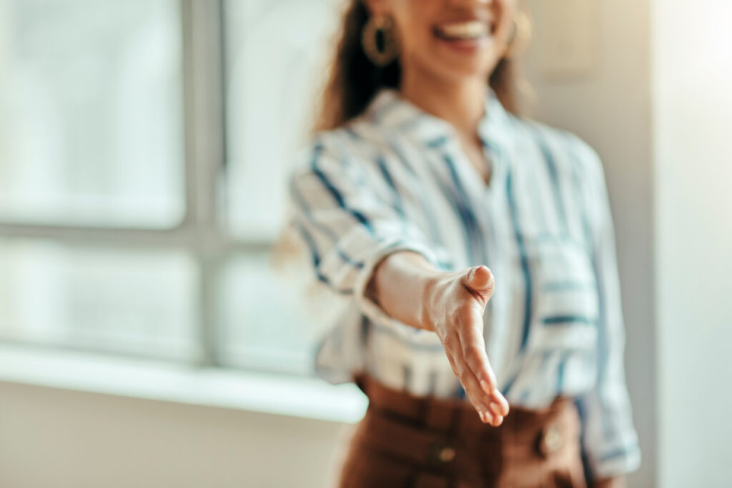 New hire extends her hand for a handshake on her first day at a new job.