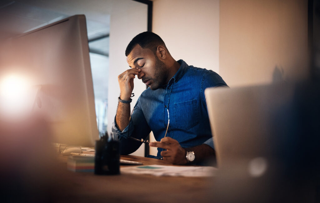Manager rubs the bridge of his nose in a sign of leadership burnout.