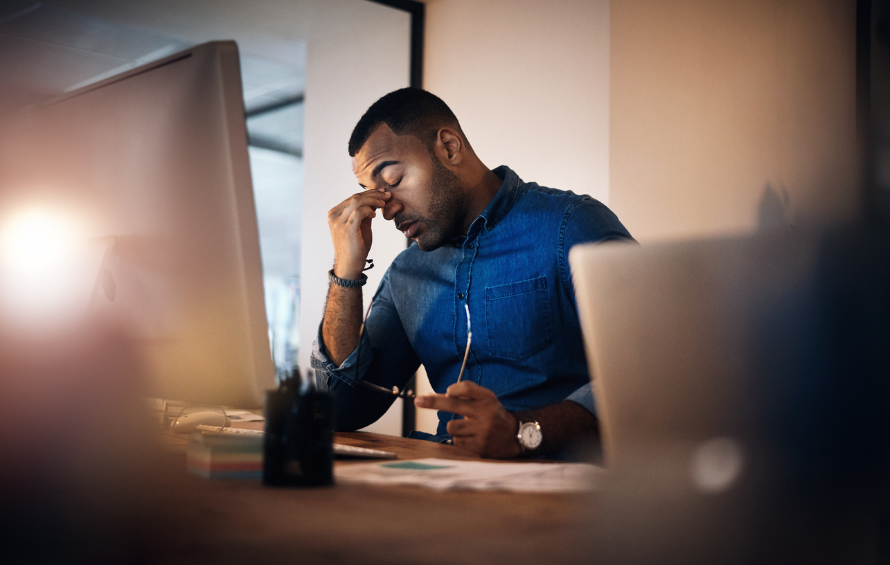 Manager rubs the bridge of his nose in a sign of leadership burnout.