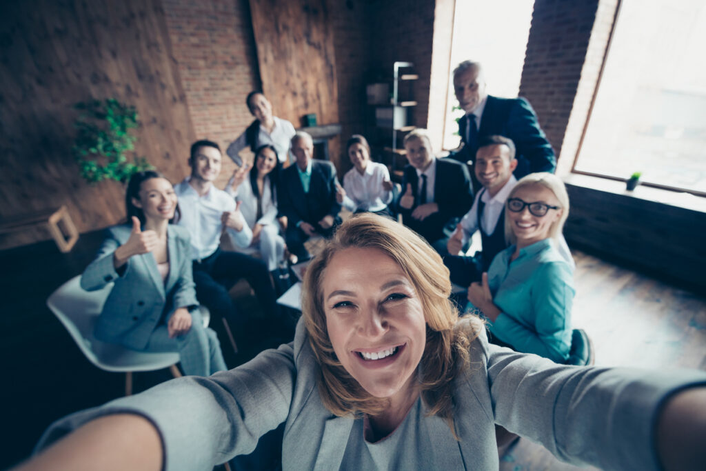 IT team takes selfie around a table, illustrating a fun culture fit.