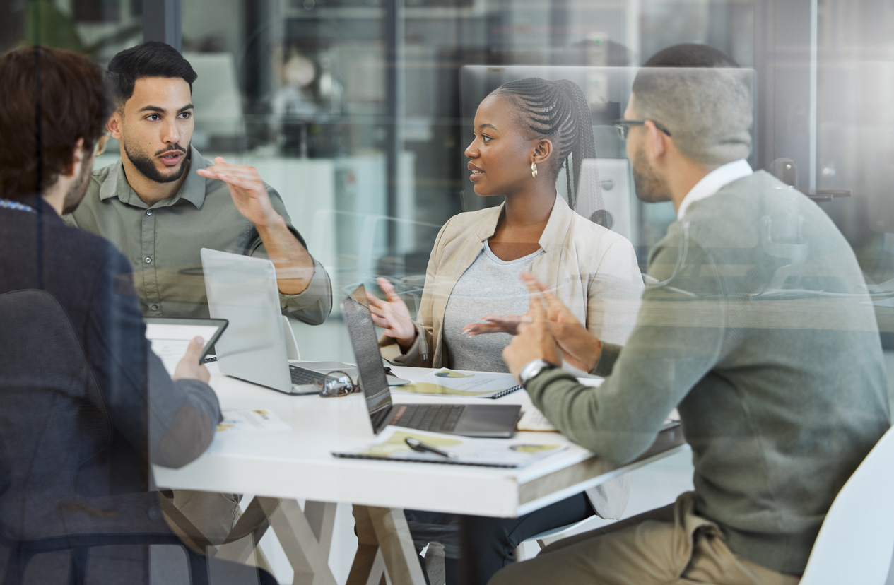 An IT team sits at a table to discuss the company's AI pilot initiatives.